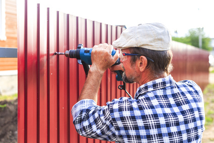 Expert fence installer drilling aluminum fence panels to hold in place